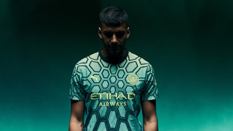 Person wearing Manchester City football jersey with hexagonal pattern, Puma logo, and Etihad Airways sponsor.