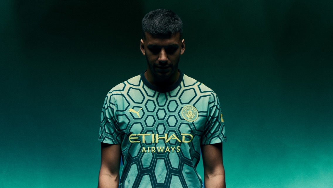 Person wearing Manchester City football jersey with hexagonal pattern, Puma logo, and Etihad Airways sponsor.