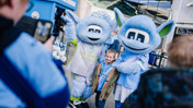 A child poses with two blue mascots outside the Manchester City merchandise store.