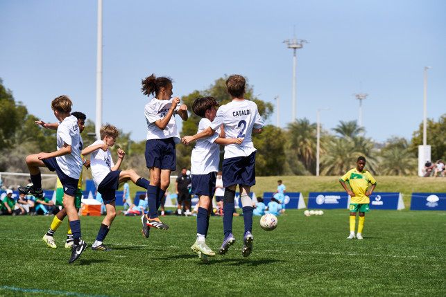 Group of young soccer players in action during a match with one cheering and others jumping.
