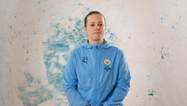 Person in a blue Manchester City jacket with Puma and 'RA' initials, standing against a marbled background.