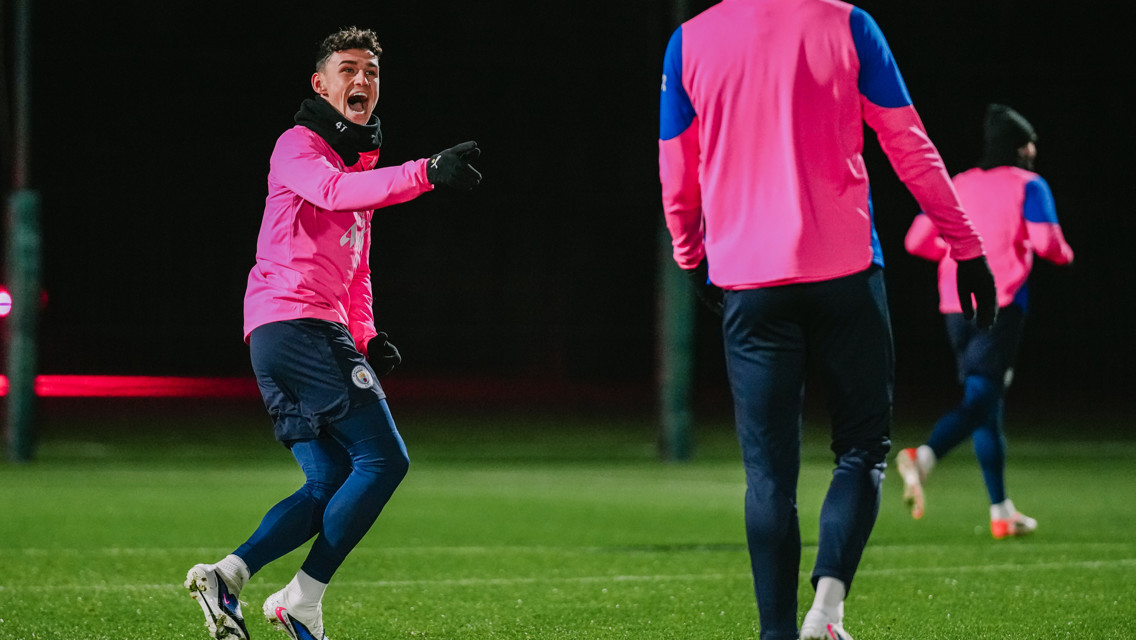 Players in pink training kits on a soccer field, participating in a session at night.