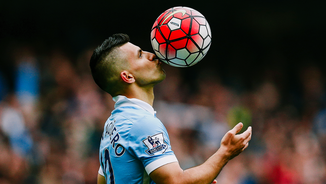 A soccer player in a Manchester City jersey heads a ball during a match.