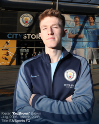 Individual stands outside the Manchester City store wearing a Manchester City jacket. Text indicates Kieran 'KezBrown' Brown from July 2016 to March 2018 for EA Sports FC.