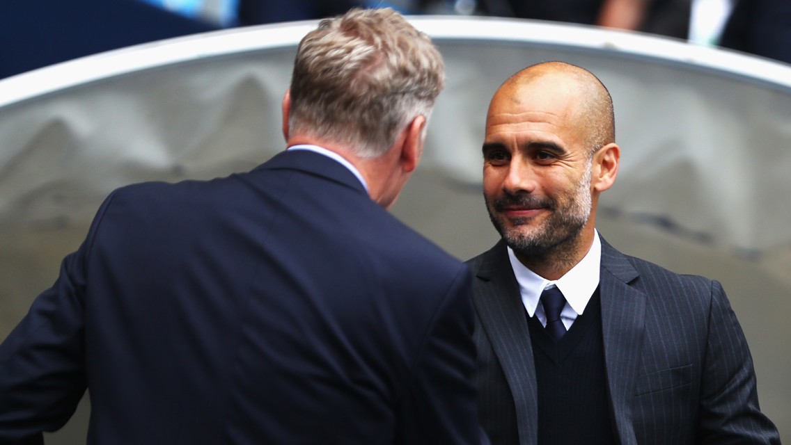 Two football managers facing each other, one with blurred face in formal attire seems to be Pep Guardiola, talking to opponent manager likely during a match setting.