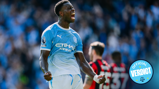 A soccer player in a Manchester City jersey celebrating a goal with clenched fists and a loud cheer on the field.