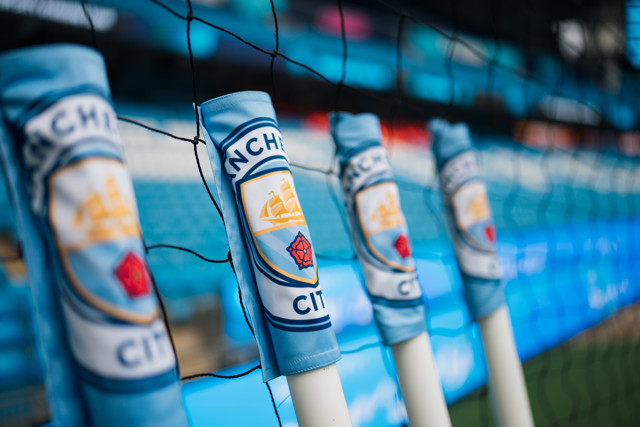 Close-up of Manchester City logos on goal net posts at a football stadium.