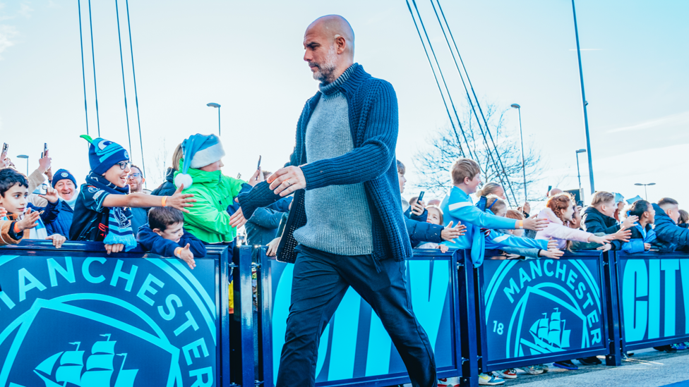 THE BOSS: Pep Guardiola arrives to a chorus of high fives from the young City supporters