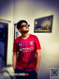 A person wearing a red Manchester City jersey with the Etihad Airways logo and Puma symbol is standing indoors with a blurred face.