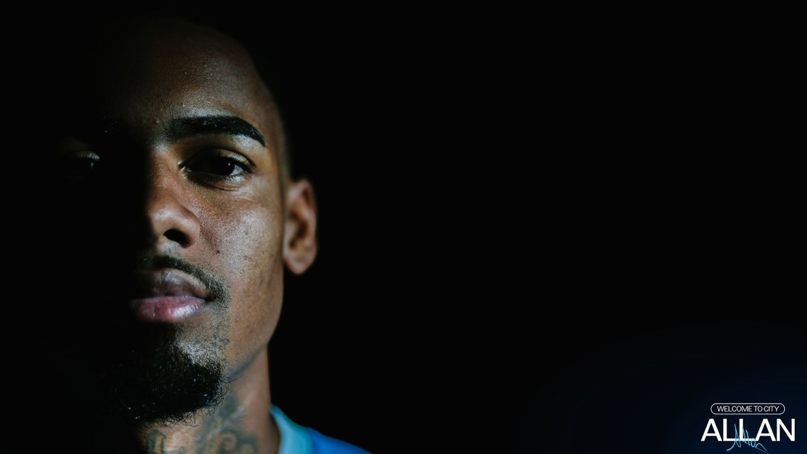A person's face is partially illuminated on one side against a dark background with 'Welcome to City' and 'Allan' text in the corner.