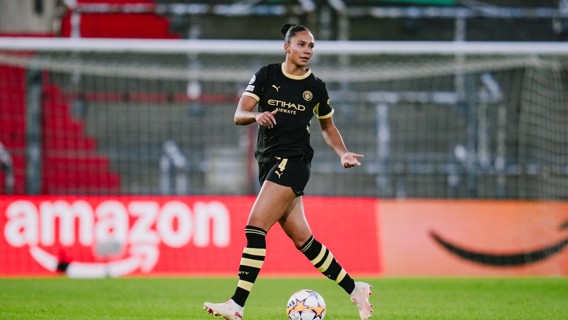 A female soccer player in a black Manchester City uniform on the field during a match.