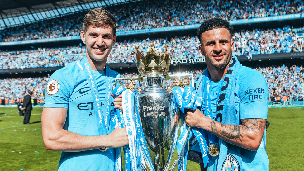 PRIMEIRO DE MUITOS : Kyle Walker e John Stones comemoram a conquista de seu primeiro troféu da Premier League no final da temporada 2017/18.