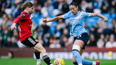 Two soccer players from Manchester City and Manchester United women's teams compete for the ball during a match.