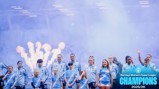 Women’s football team celebrating with Barclays Women’s Super League Champions 2025/26 text, players in blue Manchester City kits, stadium setting, fireworks in the background.