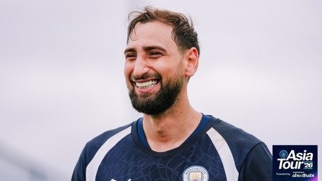 A smiling man in a Manchester City training jersey with 'Asia Tour '26' text in the corner.