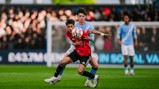 Two players from Manchester United and Manchester City compete for control of the ball during a soccer match.
