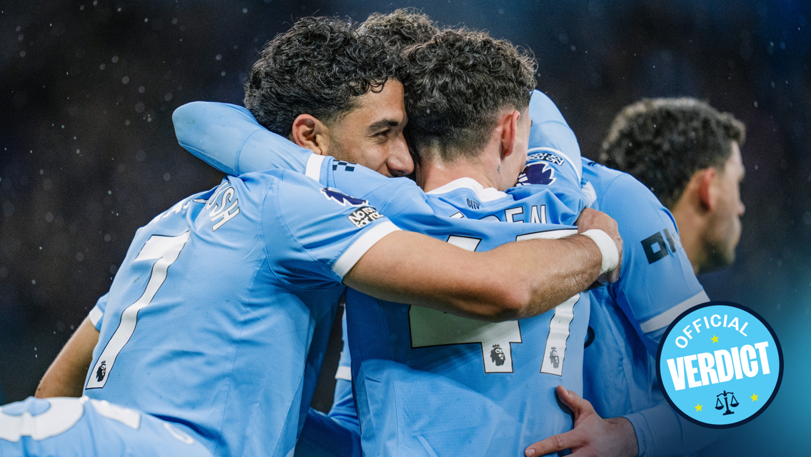 Group of football players in Manchester City jerseys hugging in celebration with an 'Official Verdict' badge.