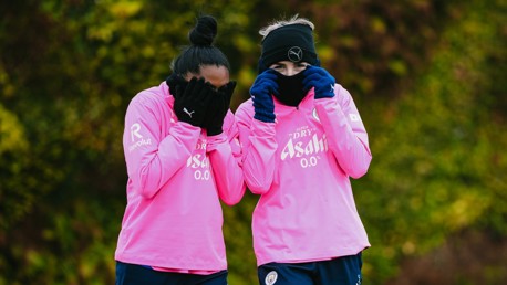 Two individuals wearing matching pink training tops during a practice session for Manchester City women's team.