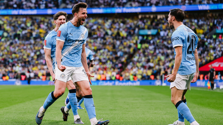 Manchester City players celebrating a goal in a football match at a stadium.