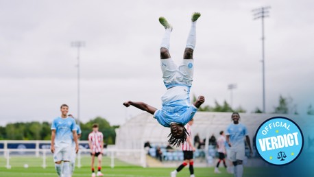A soccer player in a light blue kit performs a backflip on a field, celebrating a goal. Other players and spectators in the background. 'Official Verdict' text on the image.