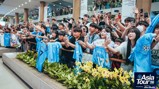 Fans at an event for Manchester City's Asia Tour '26, displaying enthusiasm and holding up team shirts while taking pictures or recording.