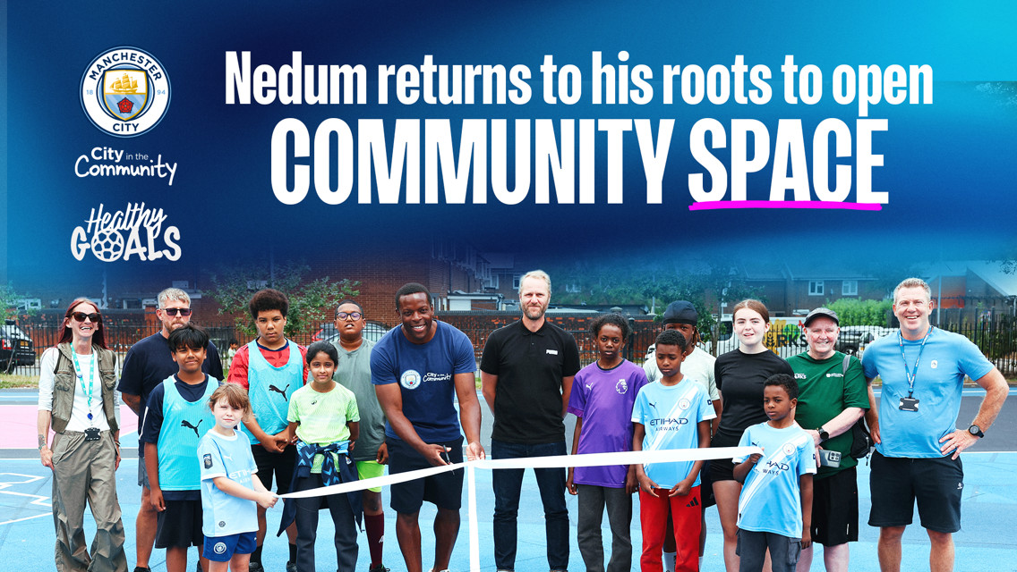 A group of people, including children, pose in front of a ribbon with text above reading 'Nedum returns to his roots to open COMMUNITY SPACE' alongside Manchester City and Healthy Goals logos.