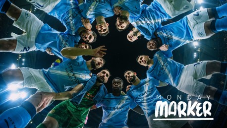 Manchester City team huddle on the field with 'Monday Marker' text overlay.