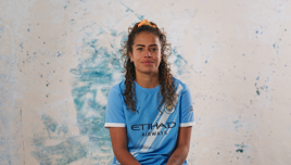 Person wearing a Manchester City women's team jersey with Etihad Airways logo.