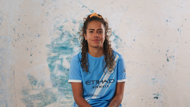 Person wearing a Manchester City women's team jersey with Etihad Airways logo.