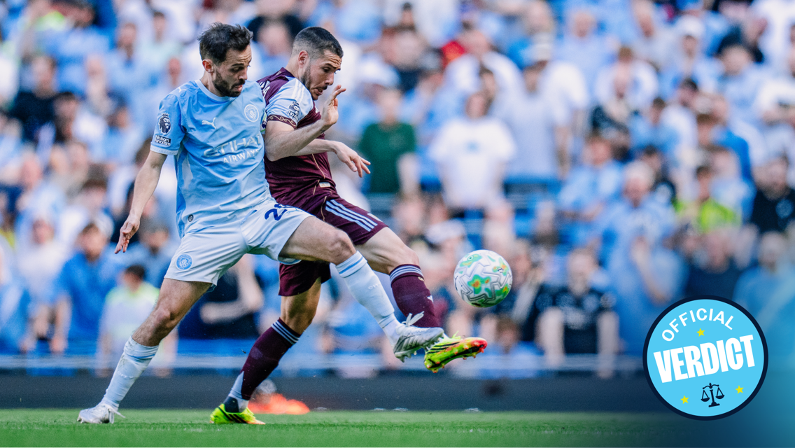 Two soccer players contesting a ball during a match, one in a light blue jersey and the other in maroon. Crowded stadium in the background with an 'Official Verdict' logo.
