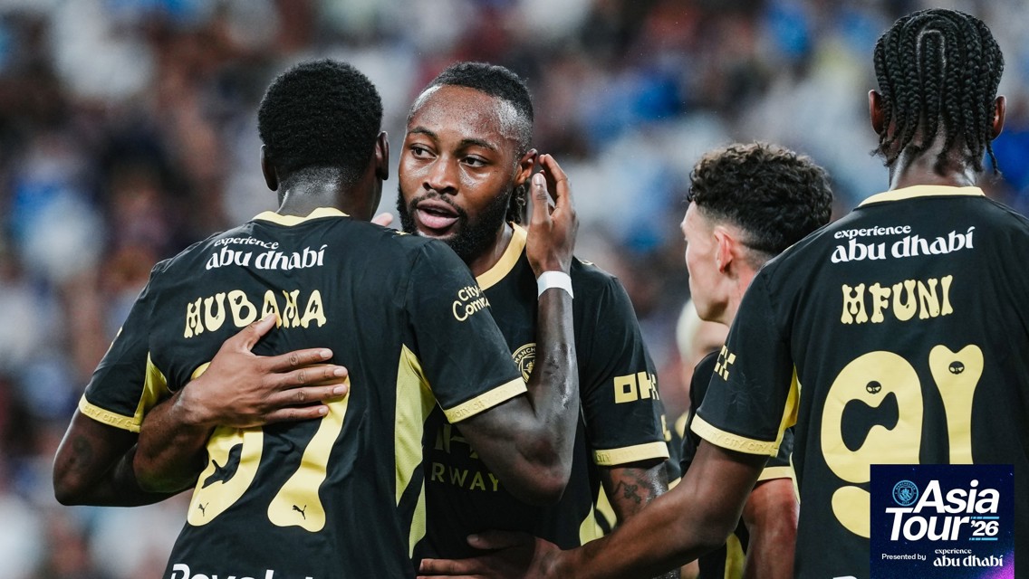 Manchester City players in black and gold kits celebrating during the Asia Tour 2026, with 'Experience Abu Dhabi' branding and the Asia Tour '26 logo visible.