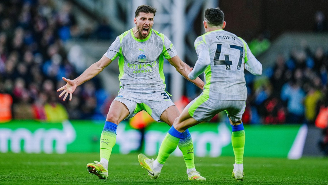 Two Manchester City players celebrating a goal during a match, one identified as Phil Foden with jersey number 47.