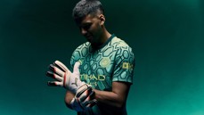 A person wearing a Manchester City goalkeeper kit, adjusting their gloves. The shirt has hexagonal patterns and the Manchester City crest is visible.