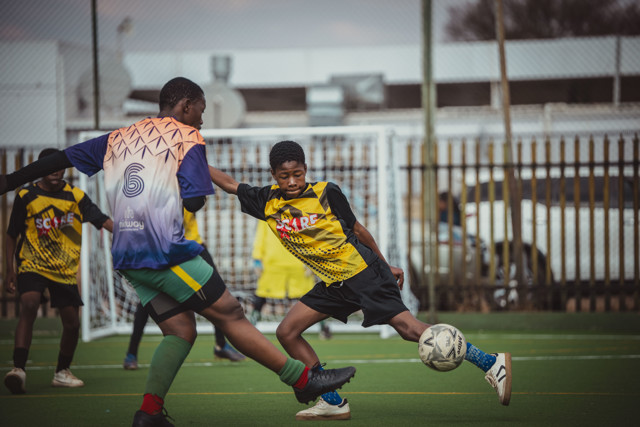 Young soccer players in action on a field, engaging in a match with one player attempting to control the ball.