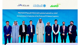 A group of people standing in front of a blue backdrop with JA Solar, Masdar, and Jinko Solar logos.