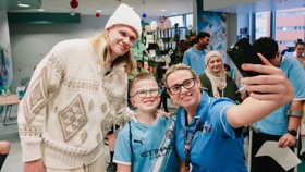 People taking a selfie in a hospital setting, one person wearing a Manchester City kit.