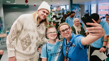 People taking a selfie in a hospital setting, one person wearing a Manchester City kit.