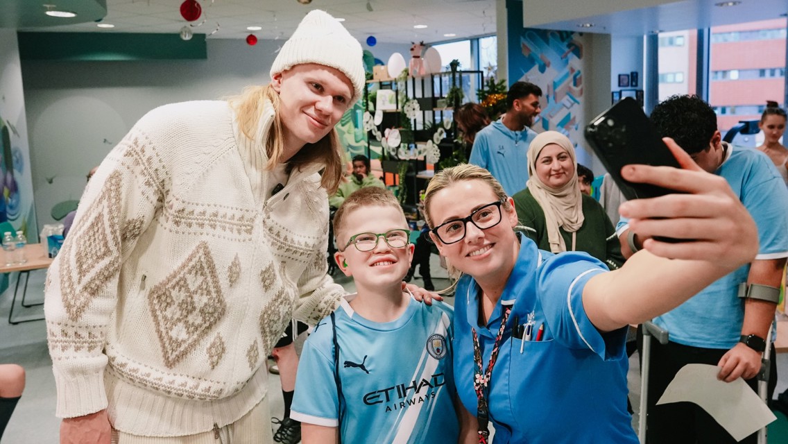 People taking a selfie in a hospital setting, one person wearing a Manchester City kit.