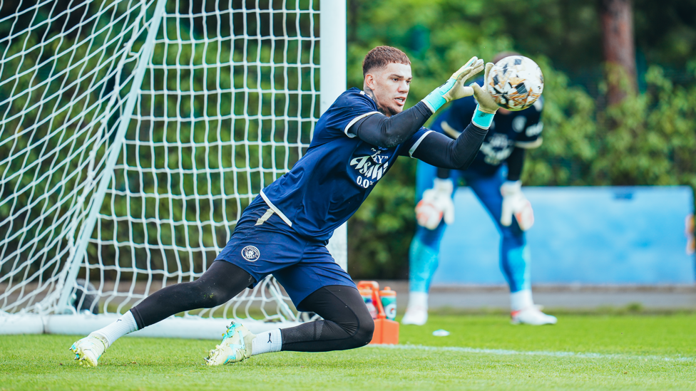 SAFE HANDS : Ederson dives to his left and catches the ball.
