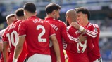 Soccer players in red jerseys celebrating together on the field.