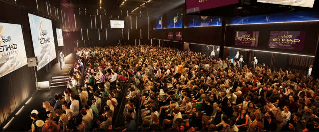 A large audience seated in a hall with Etihad Airways branding on screens. The stage features a presenter in front of the crowd.