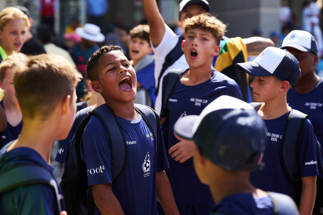 A group of young football players wearing blue jerseys and backpacks with blurred faces, participating in the Abu Dhabi Cup 2024.