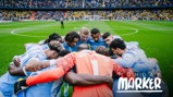 A football team in light blue jerseys huddling on the field with a stadium full of fans in the background. 'Monday Marker' text on the image.