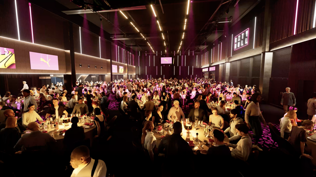 A large banquet event at City Hall with many tables and guests under pink and white lighting. Puma logo displayed on screens.