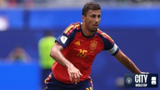 Soccer player in Spain's red and navy jersey with number 16, wearing a captain's armband, on a World Cup field.