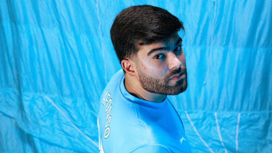 Person wearing a Manchester City jersey viewed from behind with the name 'Matteo' visible on the back, standing against a blue background.