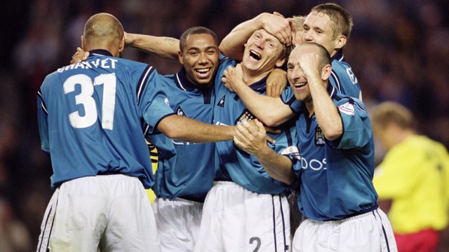 A group of Manchester City players celebrating together on the field, wearing blue jerseys, one with number 31.