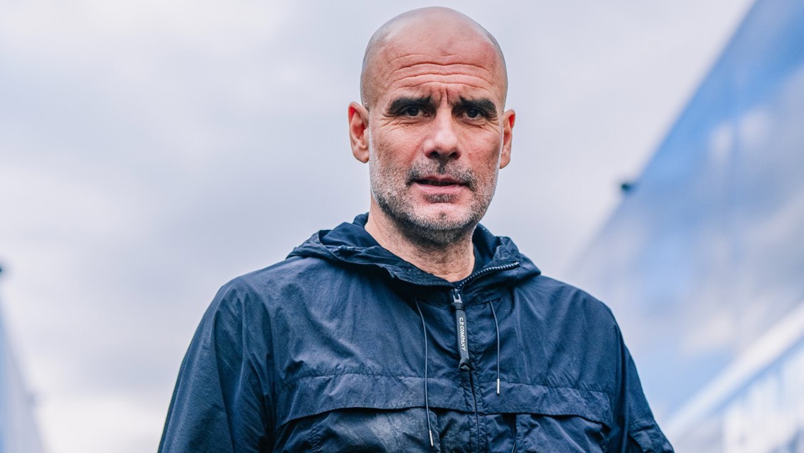 A person wearing a dark jacket stands outdoors against a cloudy sky.