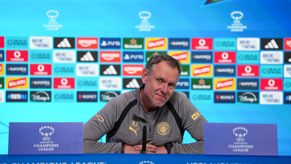 An individual at a UEFA Women's Champions League press conference with sponsor logos behind.