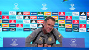 An individual at a UEFA Women's Champions League press conference with sponsor logos behind.